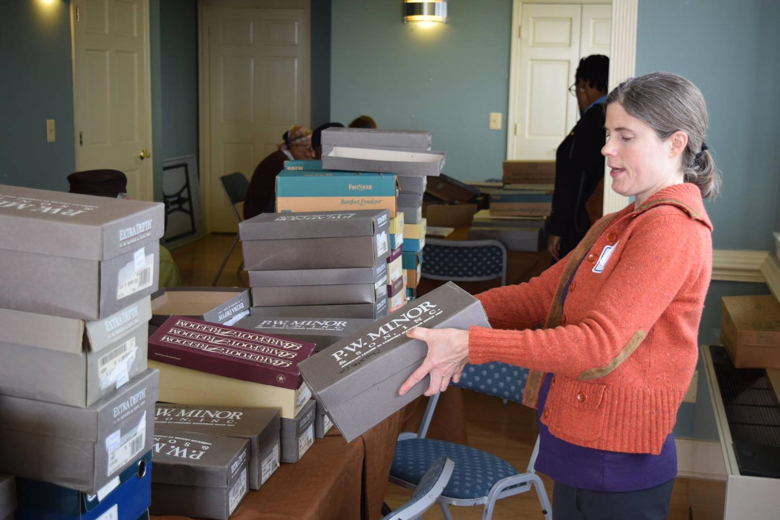 Volunteer Teresa Savarino helped distribute orthopedic shoes to Regency House residents at a special pop-up market. Iona received close to 300 pairs of shoes from Public Shoe Store in Arlington.