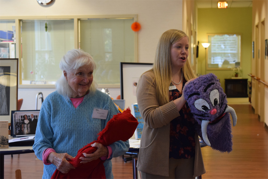 With help from our Program Manager Sarah Grogan (right), Dorothy Tucker shares two of her puppet creations during the Celebration of Achievement at Iona's Wellness & Arts Center. 